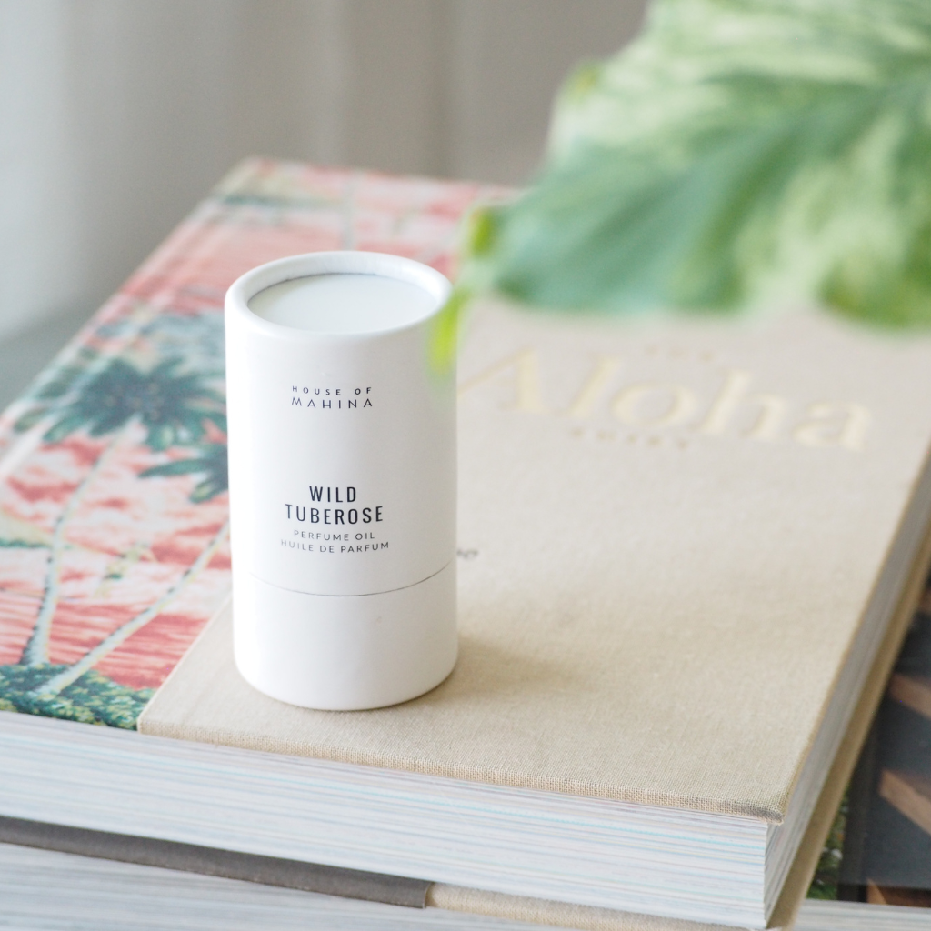 House of Mahina Wild Tuberose Perfume Oil on books with plant in background